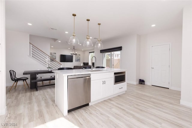 kitchen featuring a kitchen island with sink, stainless steel appliances, a sink, visible vents, and white cabinetry