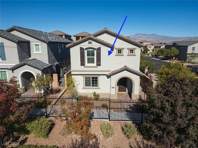 mediterranean / spanish-style home with fence, a mountain view, and a tiled roof