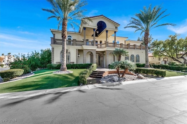 mediterranean / spanish-style home featuring a balcony and a front lawn