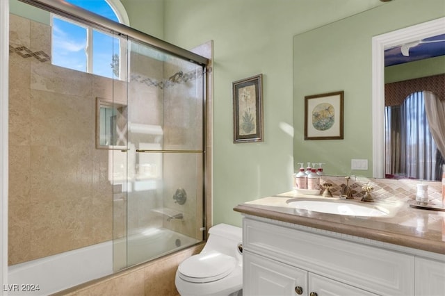 full bathroom featuring vanity, enclosed tub / shower combo, and toilet