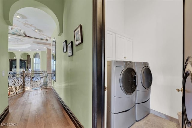 laundry room featuring cabinets, washer and dryer, and light hardwood / wood-style floors