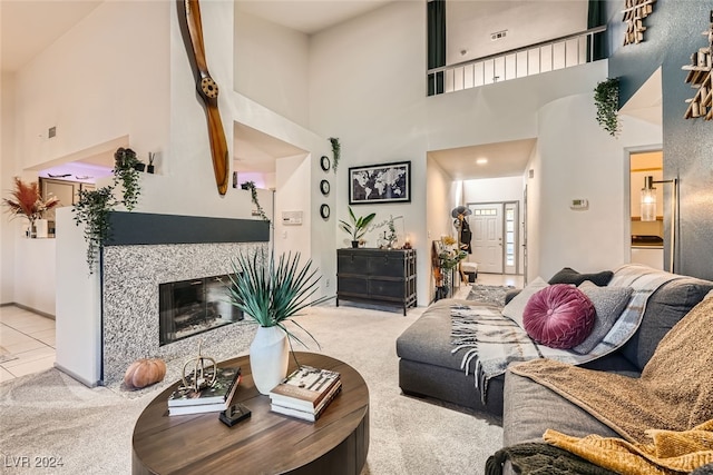 living room with a towering ceiling, light colored carpet, and a premium fireplace