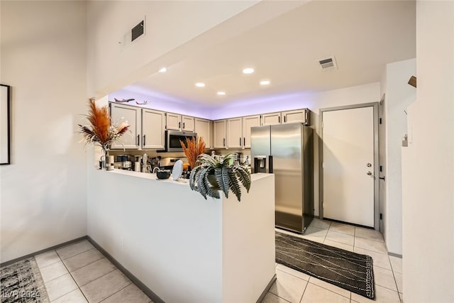 kitchen featuring kitchen peninsula, light tile patterned floors, and stainless steel appliances