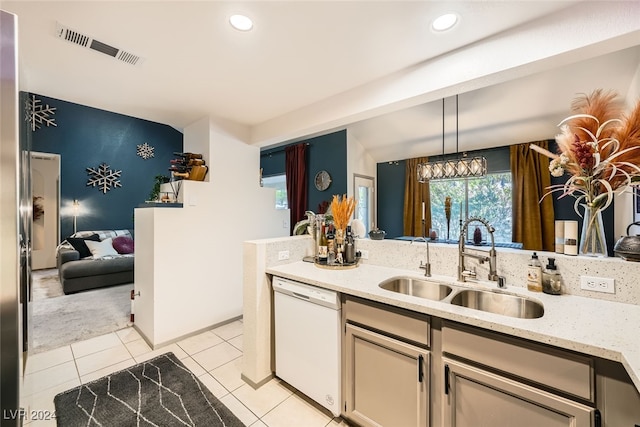 kitchen featuring light stone counters, dishwasher, hanging light fixtures, sink, and light carpet