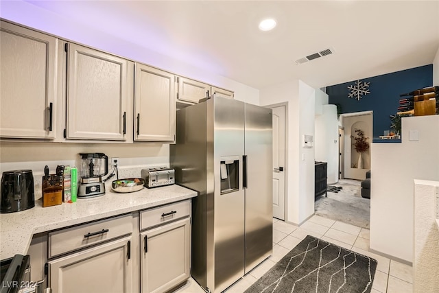 kitchen featuring light stone countertops, light tile patterned floors, and stainless steel fridge