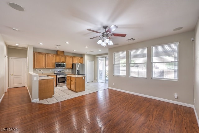 kitchen with stainless steel appliances, a wealth of natural light, light hardwood / wood-style flooring, and a kitchen island