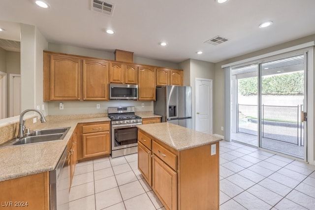 kitchen with light stone counters, sink, a kitchen island, and appliances with stainless steel finishes