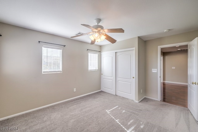 unfurnished bedroom with ceiling fan, a closet, and light colored carpet