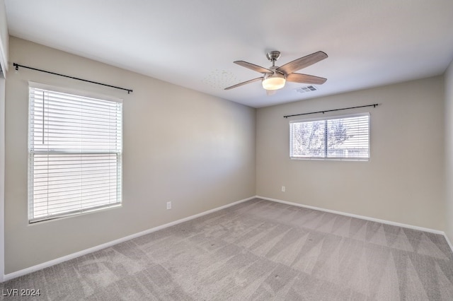 spare room featuring light carpet, ceiling fan, and plenty of natural light