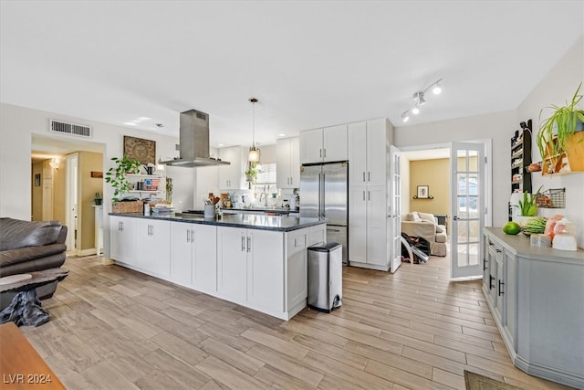 kitchen featuring island exhaust hood, white cabinetry, high end refrigerator, light wood-type flooring, and pendant lighting