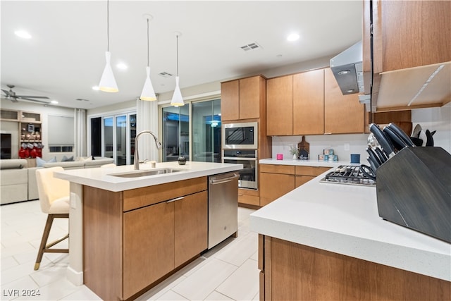 kitchen featuring sink, pendant lighting, a kitchen island with sink, exhaust hood, and appliances with stainless steel finishes