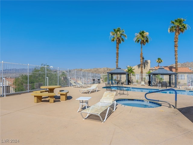 view of pool featuring a hot tub, a mountain view, a patio, and a gazebo