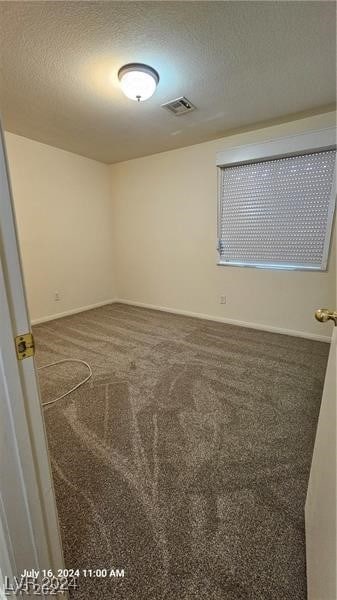 carpeted empty room featuring a textured ceiling