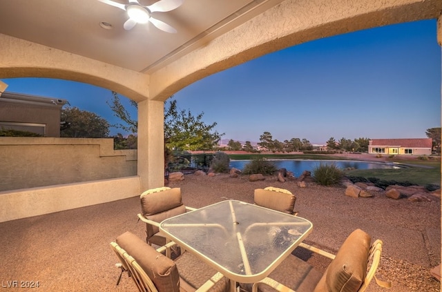 patio terrace at dusk with a water view and ceiling fan