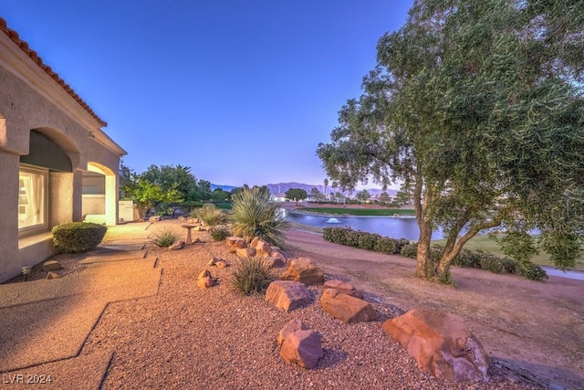 yard at dusk featuring a water and mountain view