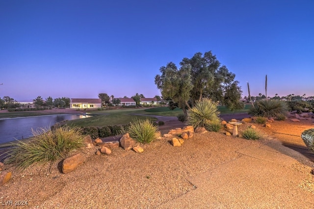 yard at dusk featuring a water view