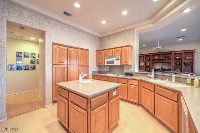 kitchen featuring an island with sink, white appliances, ceiling fan, and sink