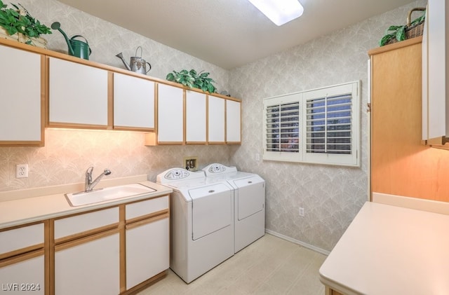 clothes washing area with washer and clothes dryer, cabinets, and sink