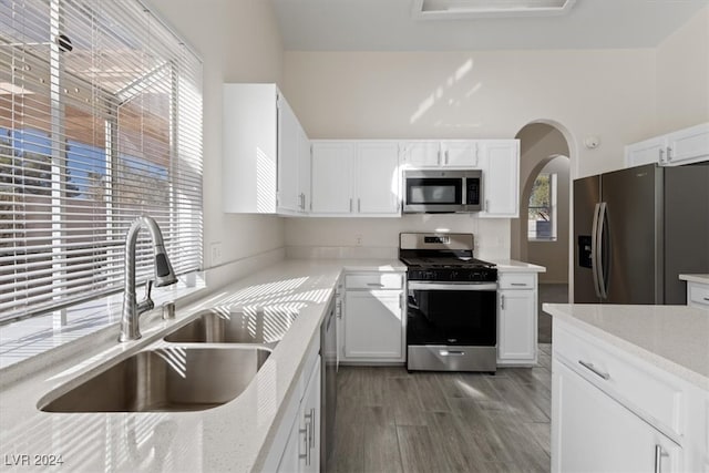 kitchen with dark wood-type flooring, light stone counters, white cabinets, sink, and appliances with stainless steel finishes