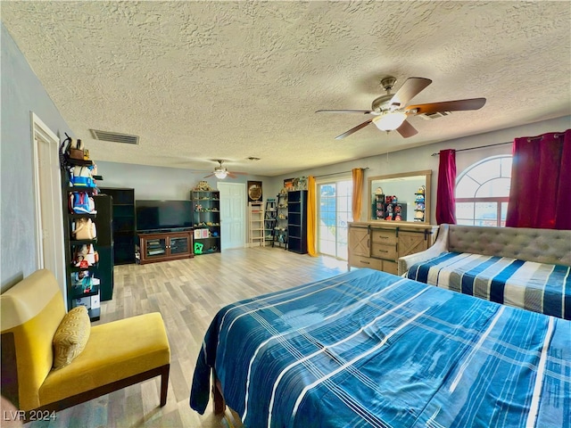 bedroom featuring hardwood / wood-style floors, a textured ceiling, multiple windows, and ceiling fan