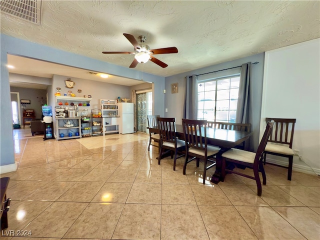 tiled dining room with a textured ceiling and ceiling fan