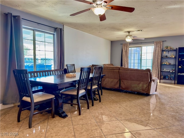 tiled dining space with a wealth of natural light, ceiling fan, and a textured ceiling