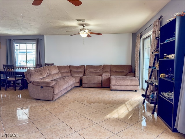 living room featuring ceiling fan, light tile patterned floors, and a textured ceiling