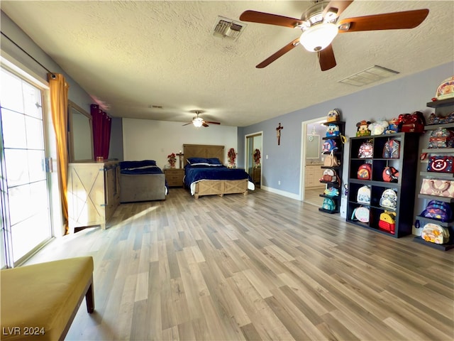 bedroom with ceiling fan, wood-type flooring, and a textured ceiling