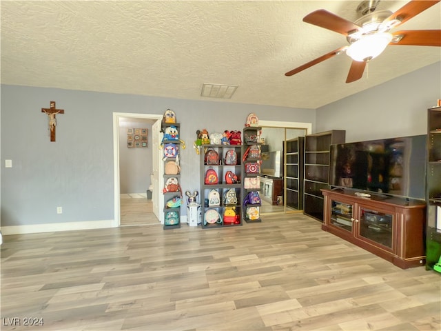 playroom featuring a textured ceiling, light hardwood / wood-style floors, and ceiling fan