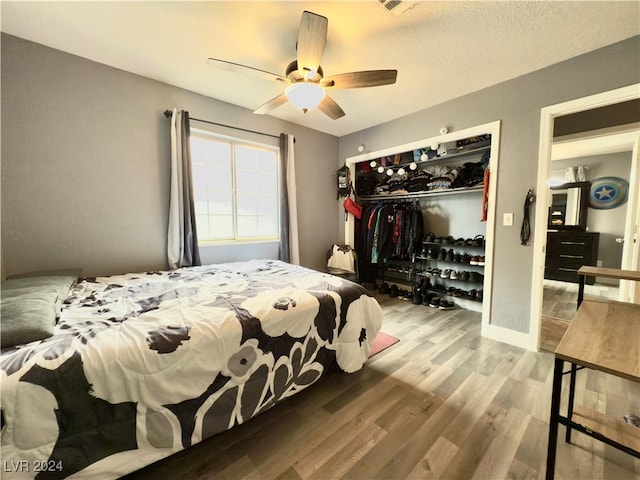 bedroom with ceiling fan, wood-type flooring, a textured ceiling, and a closet