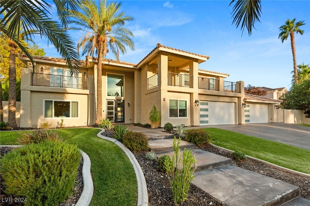 mediterranean / spanish-style house featuring a garage, a front yard, and a balcony