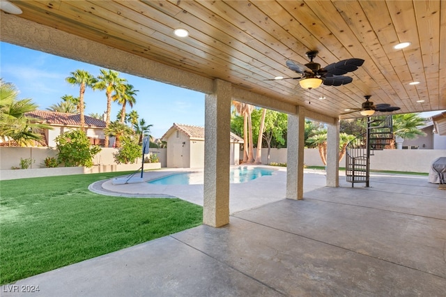 view of patio with a fenced in pool, a storage unit, and ceiling fan