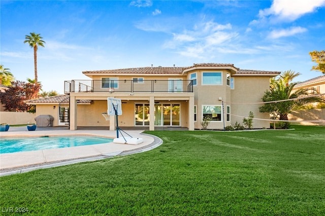 rear view of property featuring a balcony, a yard, and a patio area