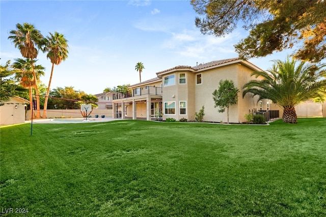 rear view of property featuring a balcony and a yard