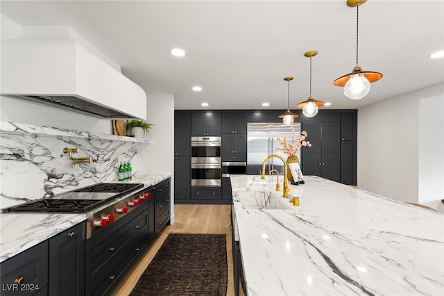 kitchen featuring stainless steel appliances, tasteful backsplash, light stone countertops, light hardwood / wood-style flooring, and pendant lighting