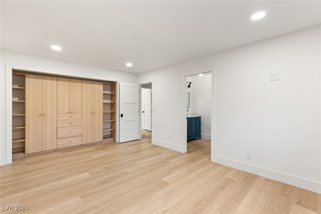 unfurnished bedroom featuring light wood-type flooring, a spacious closet, and a closet