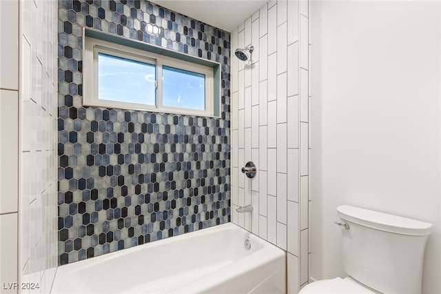 bathroom with tiled shower / bath combo and toilet