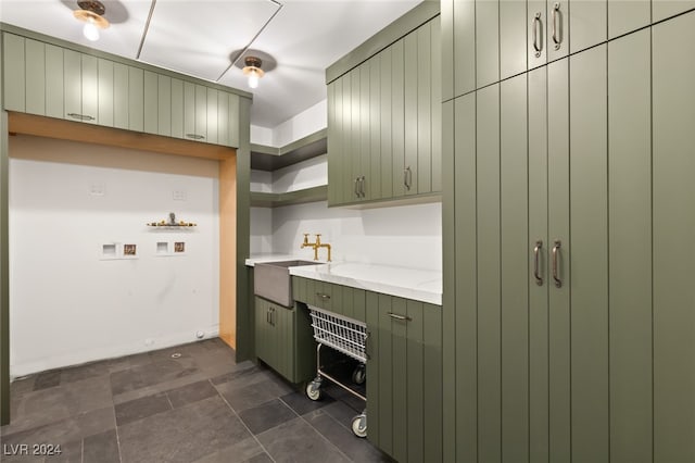 kitchen with green cabinets, sink, and light stone counters