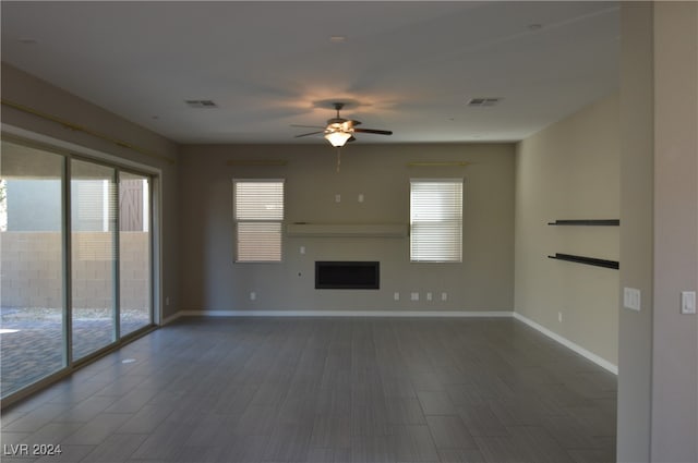 unfurnished living room with dark hardwood / wood-style flooring and ceiling fan