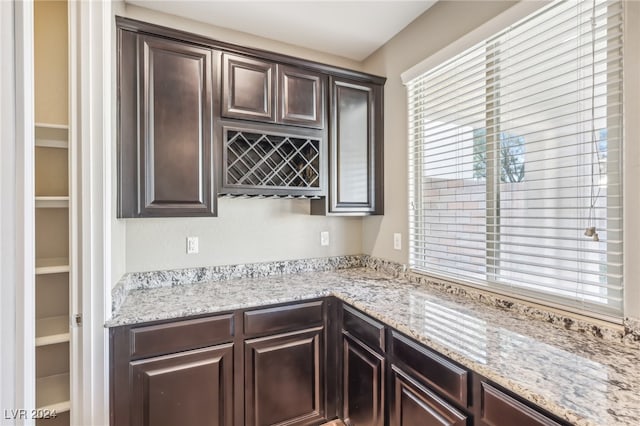 kitchen with dark brown cabinetry and light stone counters