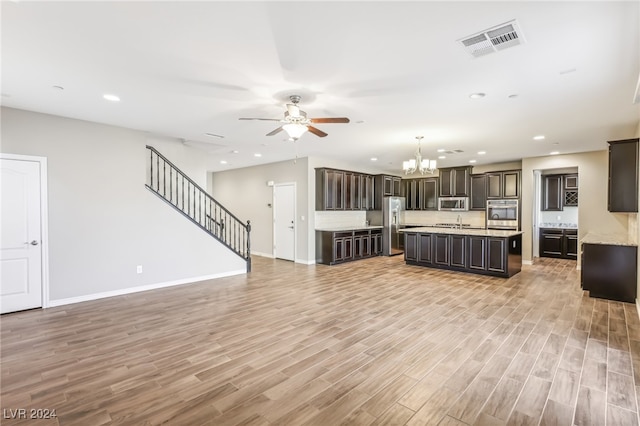 unfurnished living room with sink, light hardwood / wood-style floors, and ceiling fan with notable chandelier