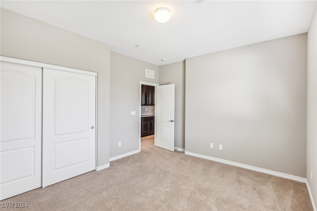 unfurnished bedroom featuring a closet and light colored carpet