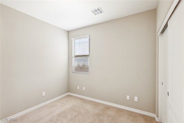 unfurnished bedroom with light carpet and a closet