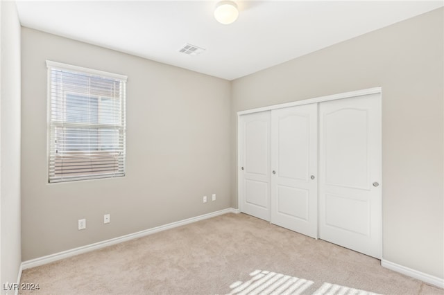 unfurnished bedroom featuring a closet and light colored carpet