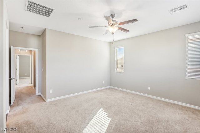 spare room featuring light colored carpet, ceiling fan, and plenty of natural light