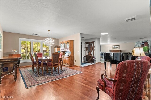 dining room featuring light wood-type flooring, a textured ceiling, and an inviting chandelier