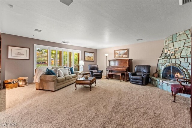 carpeted living room featuring a stone fireplace and a textured ceiling