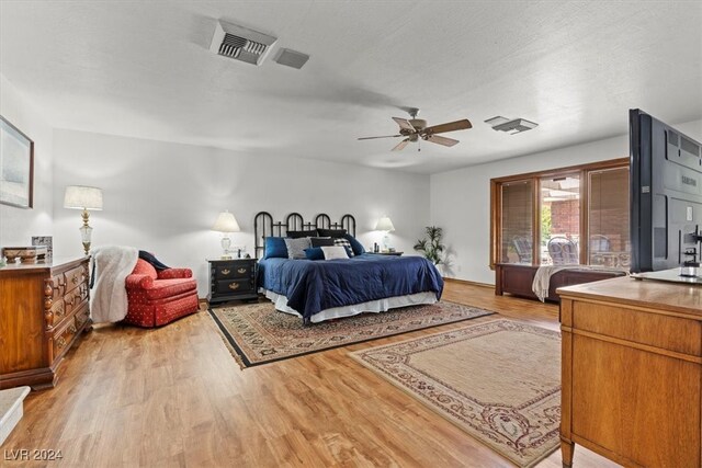 bedroom with light wood-type flooring, a textured ceiling, and ceiling fan