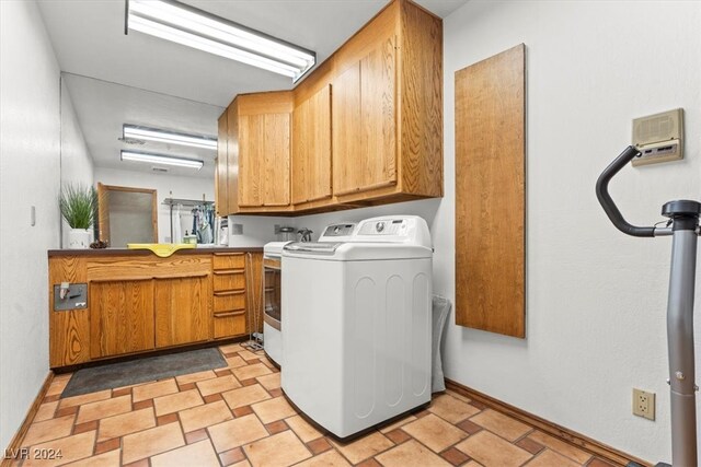 clothes washing area with cabinets and washing machine and clothes dryer