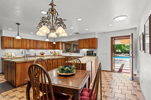 kitchen with an inviting chandelier, hanging light fixtures, a textured ceiling, sink, and backsplash